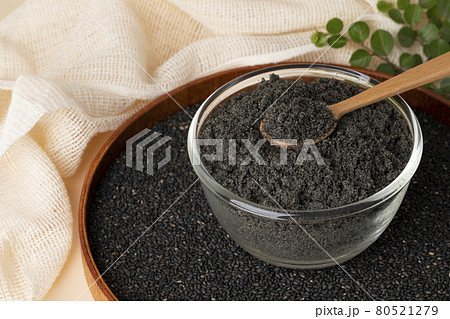 black sesame powder in glass bowl and wood spoon on black sesame seeds black sesame powder in glass bowl and wood spoon on black sesame seeds 80521279