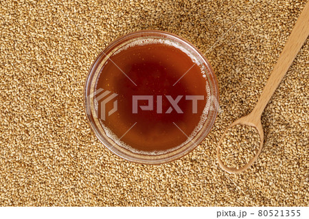 glass bowl, sesame oil and wood spoon on sesame seed background glass bowl, sesame oil and wood spoon on sesame seed background 80521355