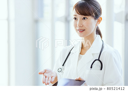 フレーム外の人物にタブレット端末の画面を見せる女性医師 80521412