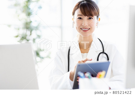 病院内でタブレット端末を見ている女性医師 80521422