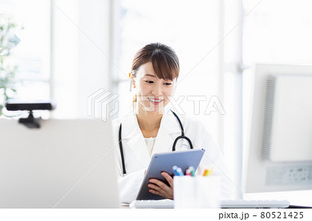 病院内でタブレット端末を見ている女性医師 病院内でタブレット端末を見ている女性医師 80521425