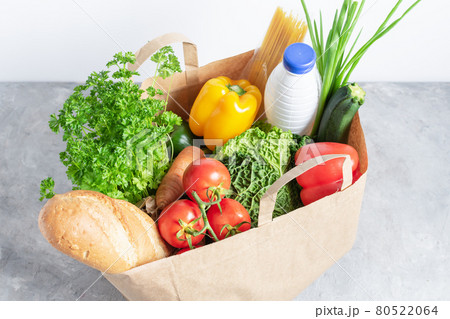Paper shopping box full of fresh organic vegetables and grocery products on grey table. 80522064