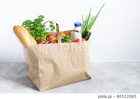 Paper shopping box full of fresh organic vegetables and grocery products on grey table. 80522065