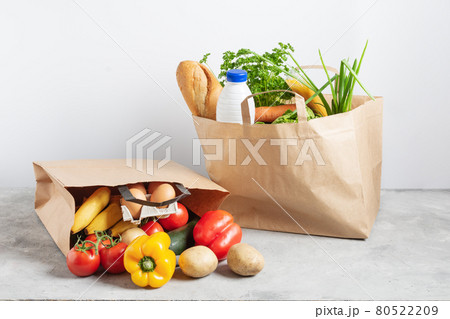 Paper shopping box full of fresh organic vegetables and grocery products on grey table. Paper shopping box full of fresh organic vegetables and grocery products on grey table. 80522209