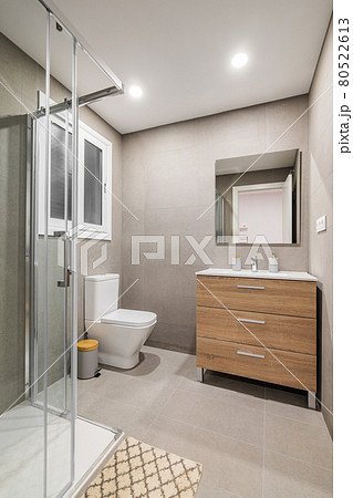 Modern refurbished bathroom with shower zone, toilet, wooden base with white sink and mirror. Modern refurbished bathroom with shower zone, toilet, wooden base with white sink and mirror. 80522613