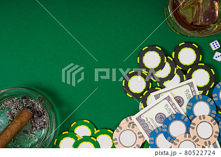 gambling, fortune and entertainment concept - close up of casino chips, whisky glass, playing cards and cigar on green table surface 80522724