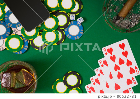 gambling, fortune and entertainment concept - close up of casino chips, whisky glass, playing cards and cigar on green table surface 80522731