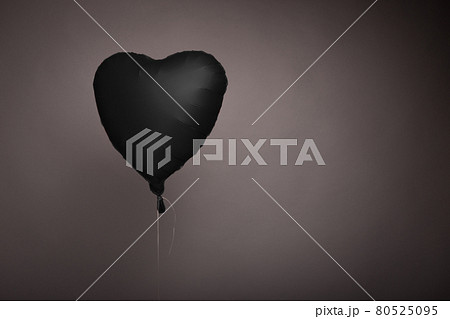 black ball in the form of a heart on a gray background in the studio 80525095