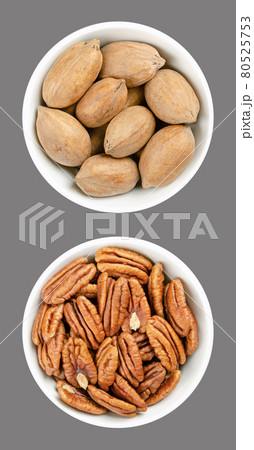 Pecan nuts, shelled and unshelled, in white bowls, over gray. Whole pecans and pecan halves, seeds and nuts of Carya illinoinensis, a popular snack. Close-up, from above, isolated, macro food photo. Pecan nuts, shelled and unshelled, in white bowls, over gray. Whole pecans and pecan halves, seeds and nuts of Carya illinoinensis, a popular snack. Close-up, from above, isolated, macro food photo. 80525753