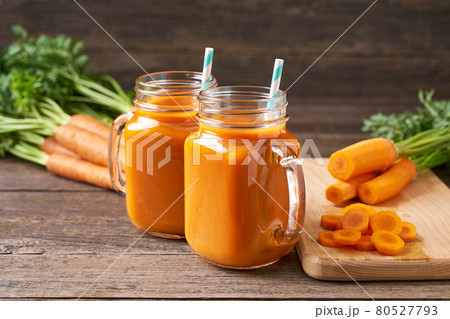 Fresh carrot juice in a mason jar glases and vegetables on a rustic wooden table. 80527793