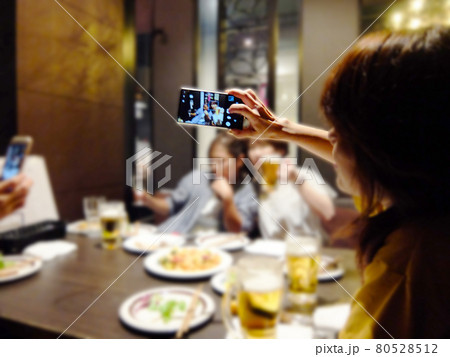 飲み会の様子をスマホで撮影する女性 の写真素材