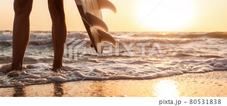 Close-up bottom pov view young adult female surfer girl legs with surfboard stand at ocean coast wave against warm sunrise or sunset sun. Sport healthy carefree freedom lifestyle vacation concept 80531838