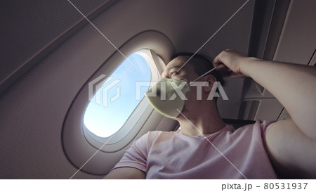 Man travel caucasian at plane with wearing protective medical mask. Male tourist at aircraft with protect respirator. Coronavirus covid-19. Man travel caucasian at plane with wearing protective medical mask. Male tourist at aircraft with protect respirator. Coronavirus covid-19. 80531937