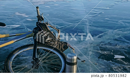 Man and his bicycle on ice. He looks at the beautiful ice in the 80531982