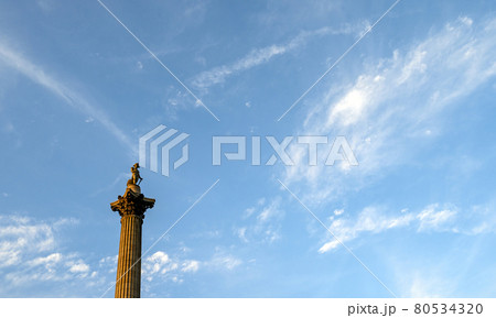 Nelson's Column in Trafalgar Square, London, UK. Nelson's Column is a main historical and tourist sight in central London. This view is the top of Nelsons Column against a blue sky and white clouds. Nelson's Column in Trafalgar Square, London, UK. Nelson's Column is a main historical and tourist sight in central London. This view is the top of Nelsons Column against a blue sky and white clouds. 80534320