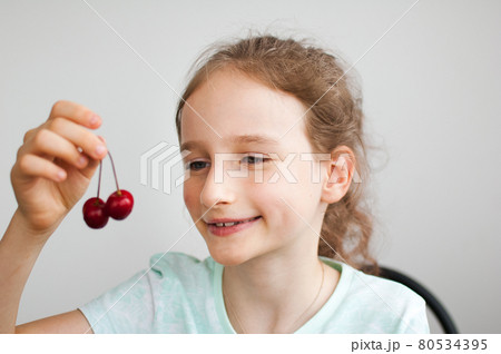 Happy surprised little girl holds cherries in hand. Healthy eating concept, healthy sweets Happy surprised little girl holds cherries in hand. Healthy eating concept, healthy sweets 80534395