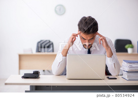 Young male employee and too much work in the office Young male employee and too much work in the office 80534924
