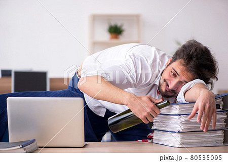 Young alcohol addicted male employee working in the office Young alcohol addicted male employee working in the office 80535095