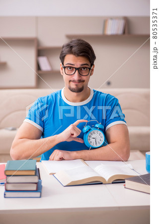Young male student studying at home in time management concept Young male student studying at home in time management concept 80535371