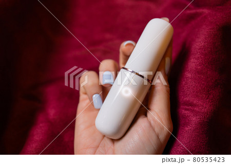 Woman in bedroom holding vibrator in hand. Woman in bedroom holding vibrator in hand. 80535423