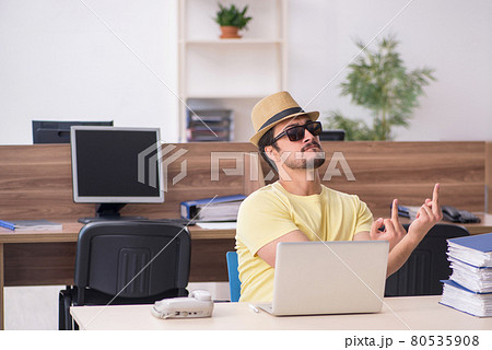 Young male employee preparing for trip at workplace 80535908