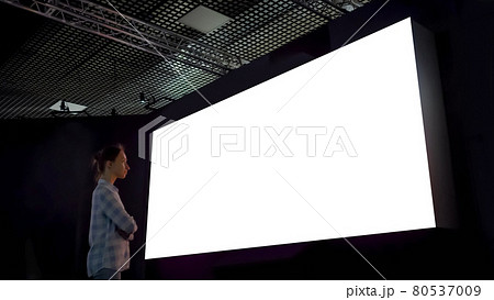 Woman looking at blank large interactive wall display - white screen concept Woman looking at blank large interactive wall display - white screen concept 80537009