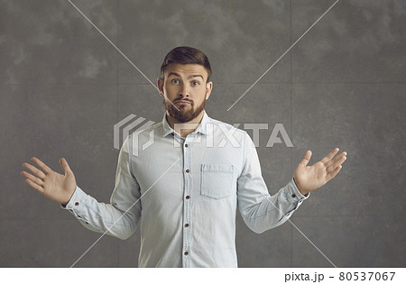 Portrait of a young man shrugging shoulders with a confused or indifferent face expression 80537067