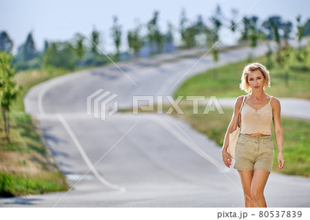Slim white female with blonde hair goes on road. Slim white female with blonde hair goes on road. 80537839