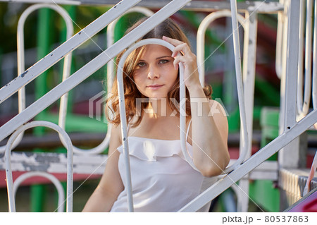 Attractive serious woman sits behind fence outdoors. 80537863