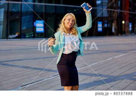 Happy female manager dances near business center. Happy female manager dances near business center. 80537888