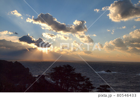 夕日が雲の間から光のカーテンの様に海面を照らす。オレンジ色の光が