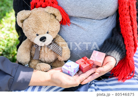 Cropped shot images of lovely couple, husband give a small present box to his pregnant wife for celebrate to their baby. Conceptual of couple expecting a baby with love. 80546875