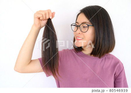 Portrait of attractive Asian woman holding a ponytail cutting hair for donation. Usable hair can turn your long locks into free or low-cost wigs for people with cancer. 80546939