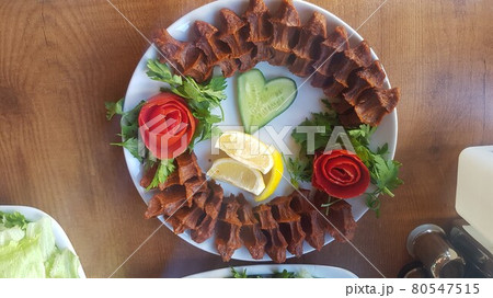Cig kofte (raw meatball) with lettuce, tomato, pickle and lemon on the white plate. Turkish food Raw Meat ( Cig Kofte ) from traditional Turkish cuisine Cig kofte (raw meatball) with lettuce, tomato, pickle and lemon on the white plate. Turkish food Raw Meat ( Cig Kofte ) from traditional Turkish cuisine 80547515