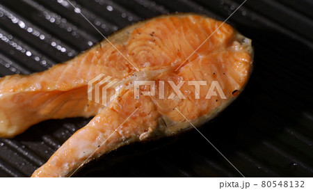 Female cook seasoning black pepper salmon steaks on grill. 80548132