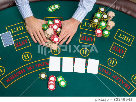 Closeup of poker player with playing cards and chips Closeup of poker player with playing cards and chips 80549942