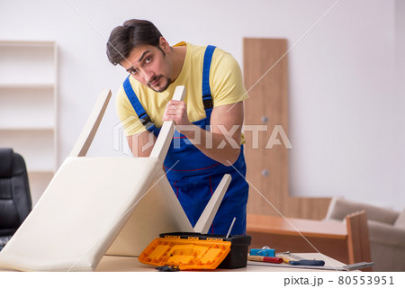 Young male carpenter repairing chair in the office Young male carpenter repairing chair in the office 80553951