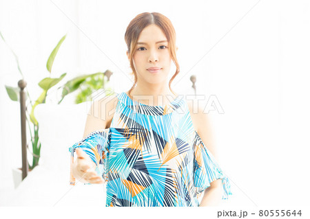 明るい部屋の窓際で、握手のジェスチャーをする、ワンピースを着た若い女性 明るい部屋の窓際で、握手のジェスチャーをする、ワンピースを着た若い女性 80555644
