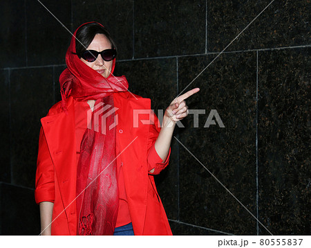 A girl in red clothes stands against a background of black granite. Copy Space A girl in red clothes stands against a background of black granite. Copy Space 80555837