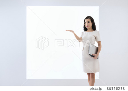 パネルの前にノートパソコンを持ってお勧めポーズをする若い女性 パネルの前にノートパソコンを持ってお勧めポーズをする若い女性 80556238