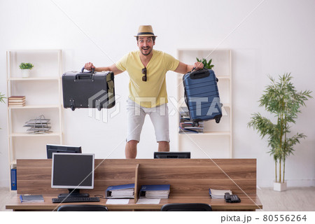 Young male employee preparing for trip at workplace Young male employee preparing for trip at workplace 80556264