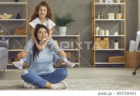 Happy single mother and her little daughter sitting on a warm rug in the living room 80558461