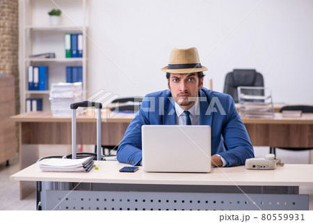 Young male employee preparing for trip in the office 80559931