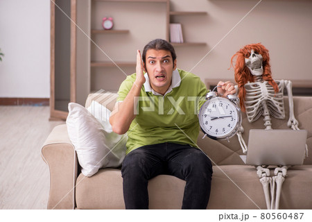 Young man with female skeleton in time management concept Young man with female skeleton in time management concept 80560487
