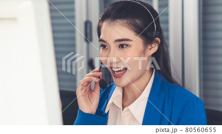 Businesswoman wearing headset working actively in office Businesswoman wearing headset working actively in office 80560655