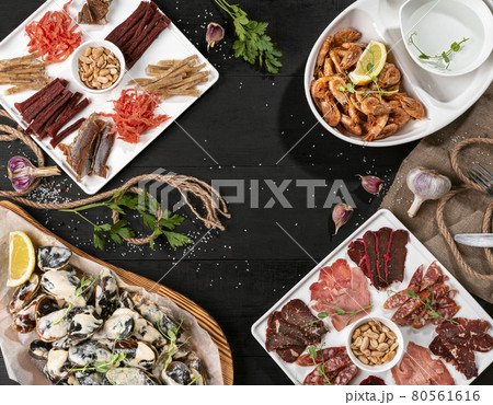 Cold cuts, dried fish platter, shrimps and mussels on black wooden table Cold cuts, dried fish platter, shrimps and mussels on black wooden table 80561616
