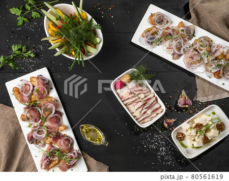 Baked potatoes with fish, sliced pork belly, cheese and vegetables on table 80561619