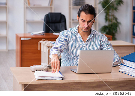 Young male employee sitting in the office Young male employee sitting in the office 80562045