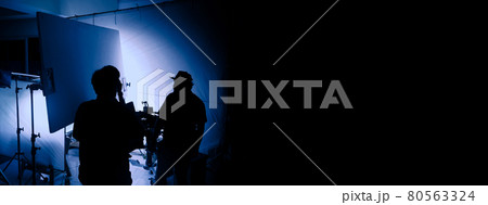 Video production behind the scenes. Making of TV commercial movie that film crew team lightman and cameraman working together with film director in studio. film production concept. Silhouette style. Video production behind the scenes. Making of TV commercial movie that film crew team lightman and cameraman working together with film director in studio. film production concept. Silhouette style. 80563324