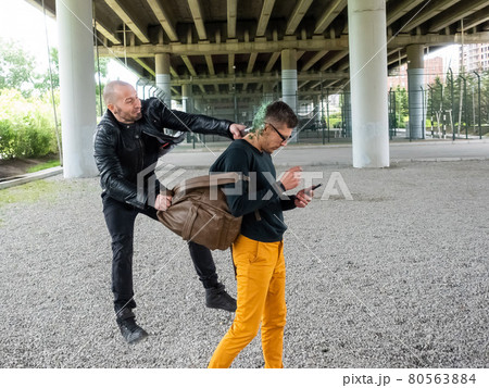 The thug breaks the bottle on the man's head and steals the backpack. Attack with the purpose of theft The thug breaks the bottle on the man's head and steals the backpack. Attack with the purpose of theft 80563884